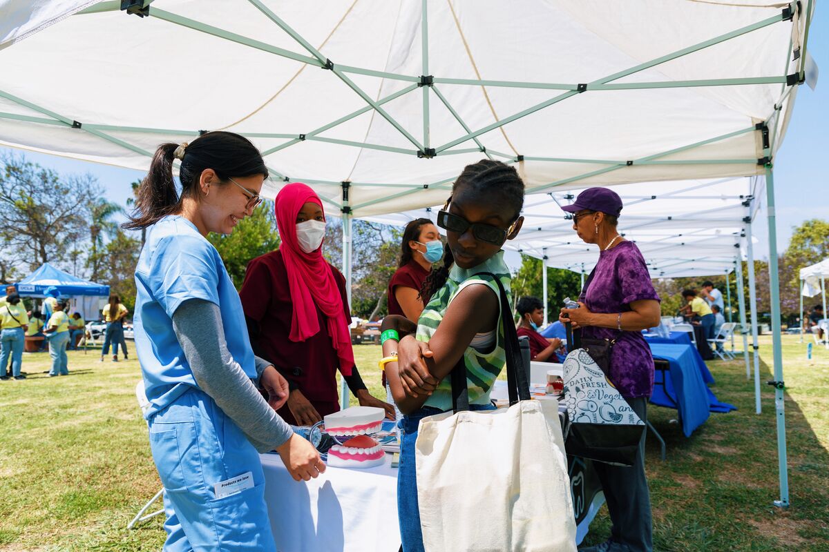 Medical students in scrubs teaching dental health at a community screening booth