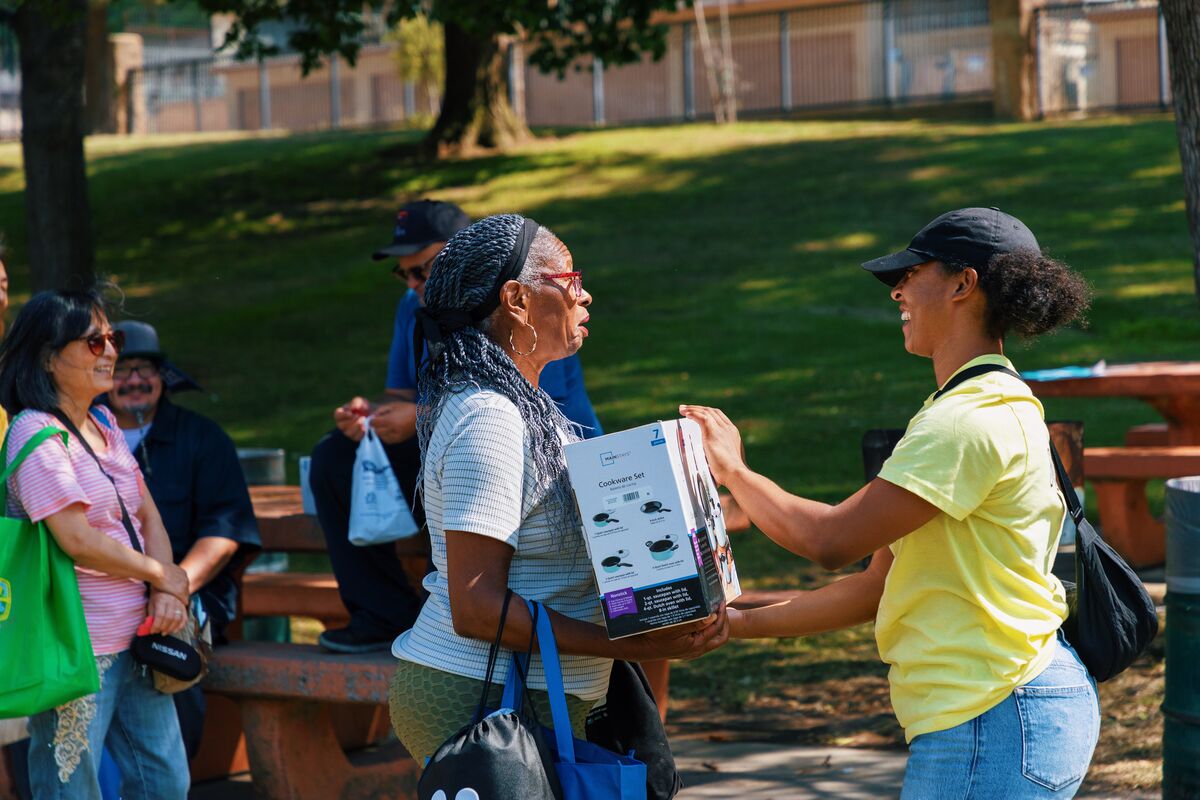 Volunteer handing a cookware prize to a smiling community member