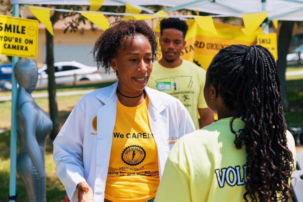 Gold Standard Urology physician in white coat connecting with a volunteer at the health fair