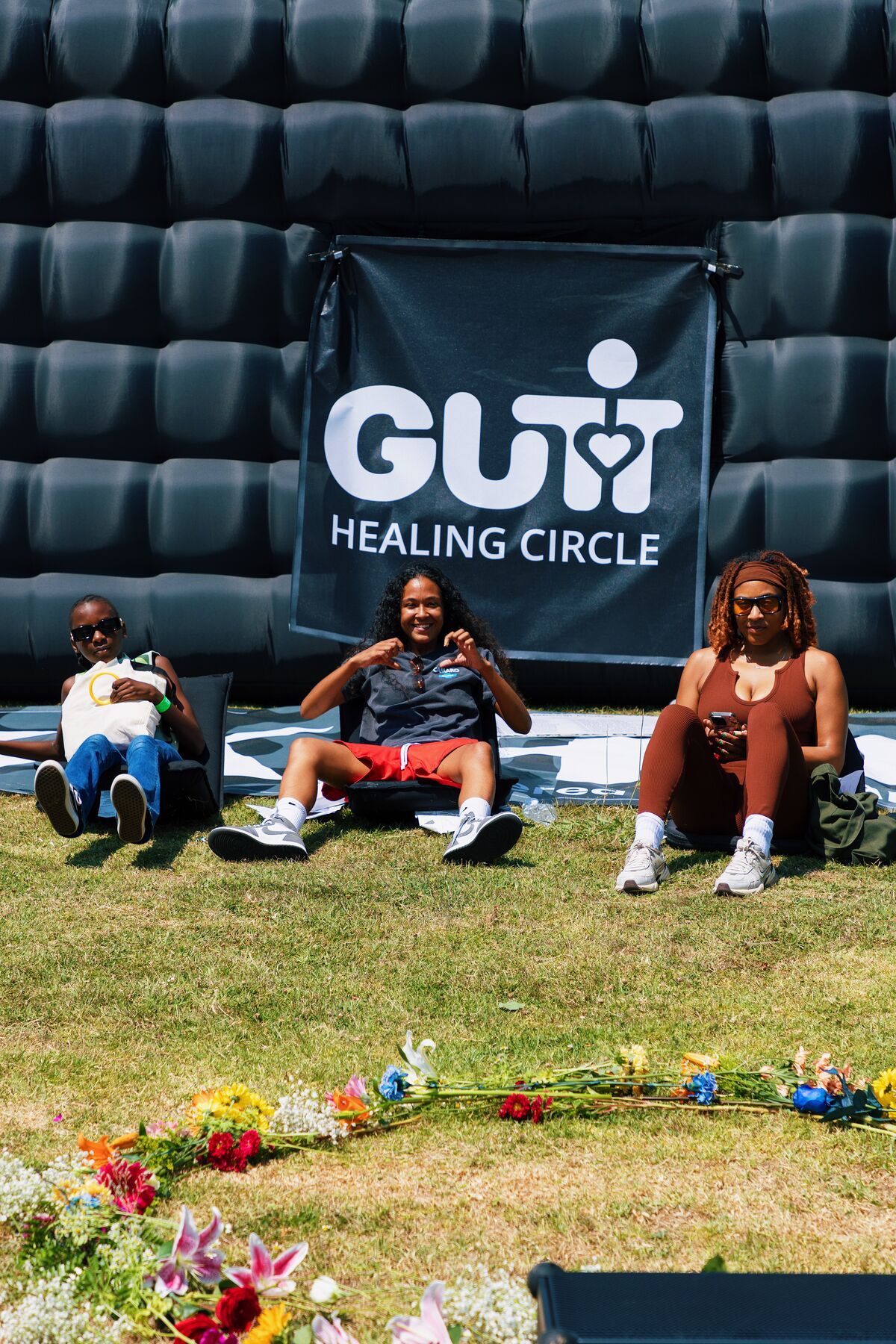 Community members seated in front of the GUT Healing Circle inflatable