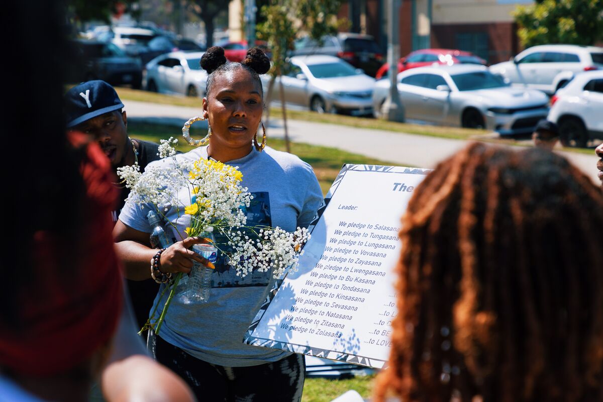 Pledge ceremony leader holding flowers and reading from the Mbongi Pledge