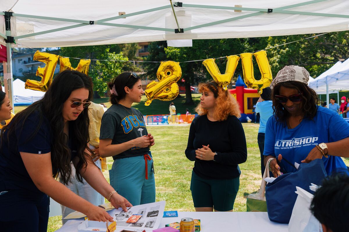 UCLA medical students engaging community members at the UV and ME skin health booth with gold balloons