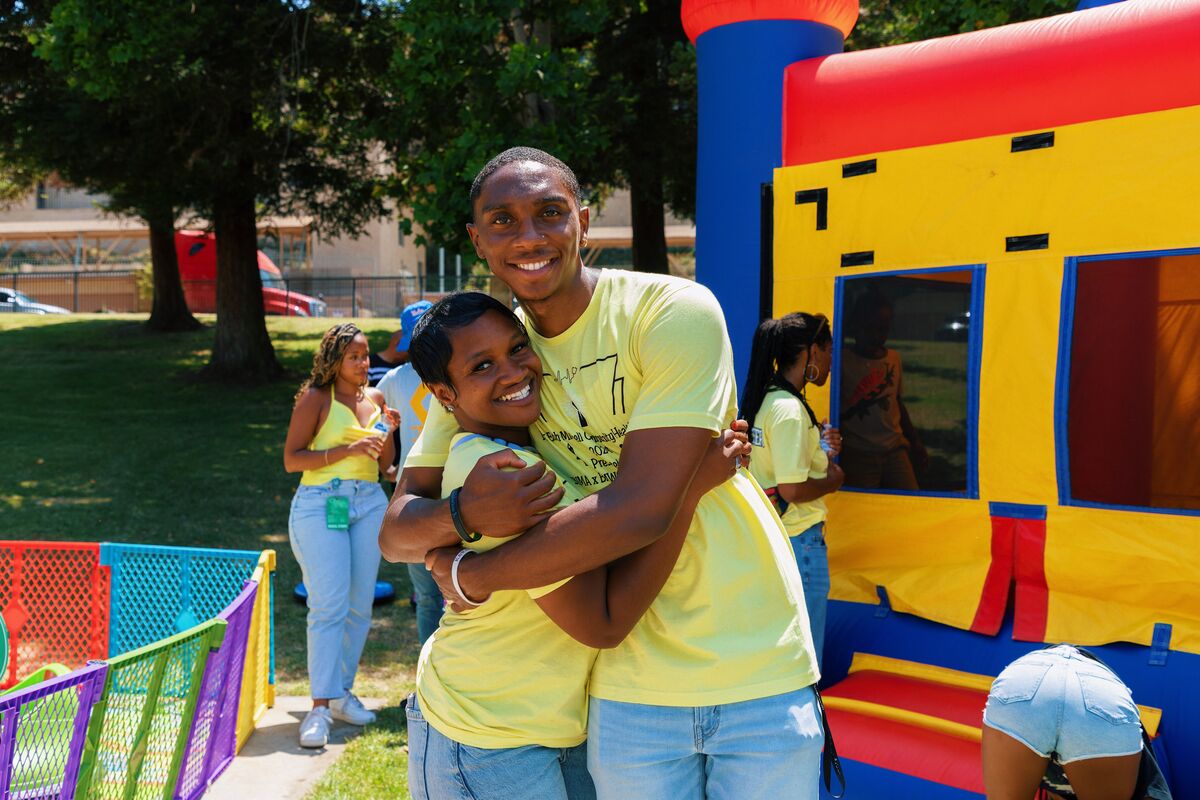Two BWP-LA volunteers embracing joyfully in front of the bounce house